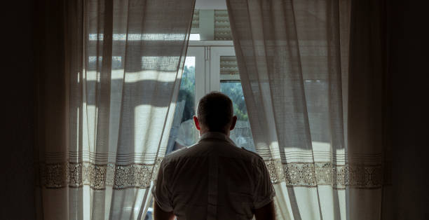 hombre mayor mirando por la ventana mientras espera resolución de una herencia